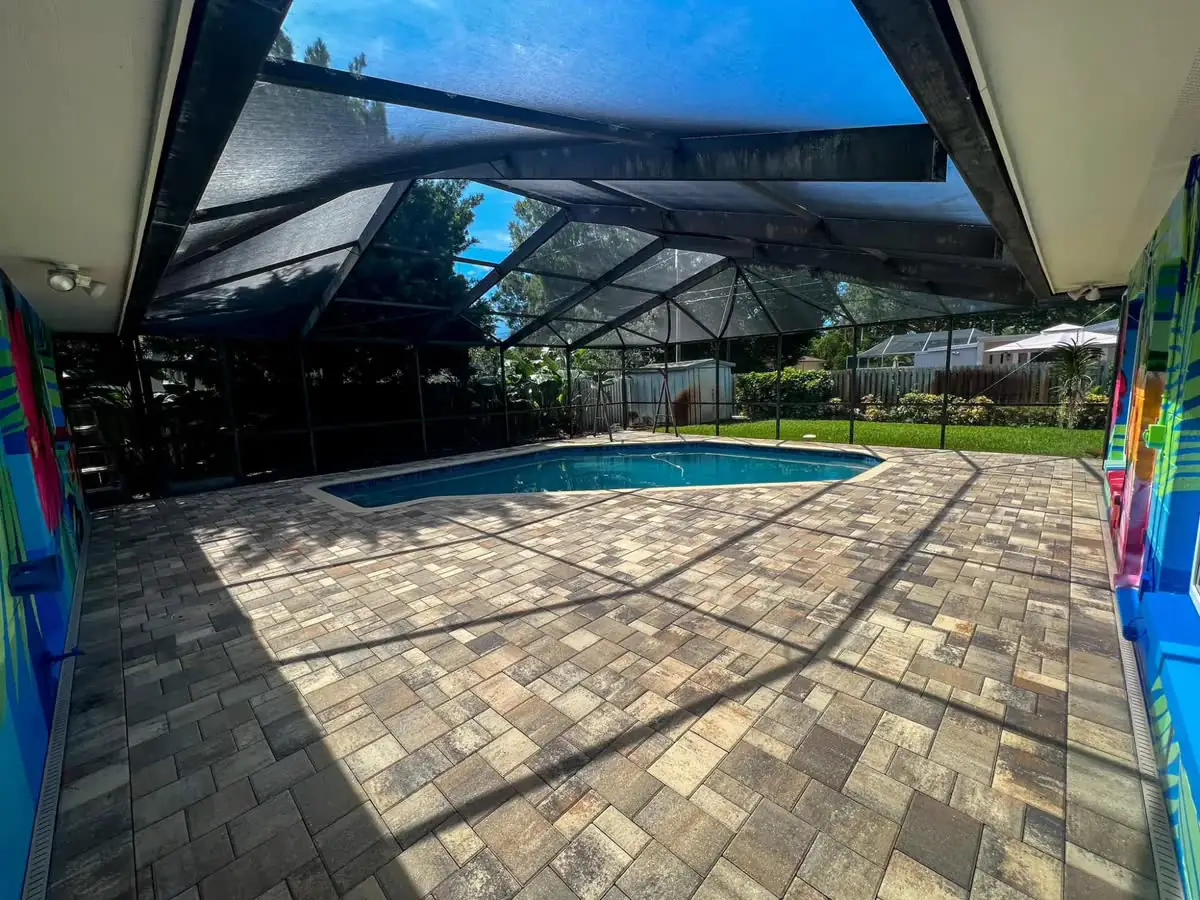 After: the same paver pool deck under the screen cage, cleaned and sealed, the warm colors of the pavers back.