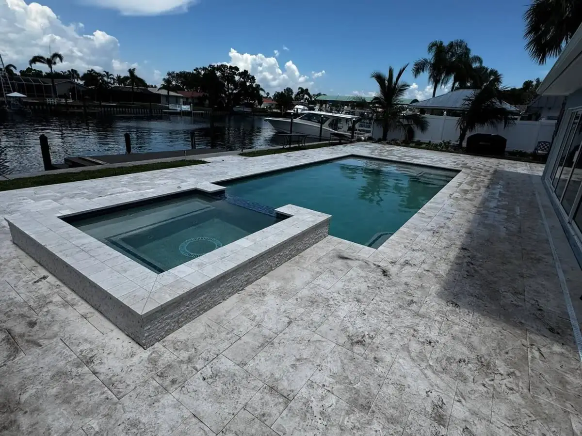 Before: a travertine pool deck and spa on a canal, the stone dull and darkened.