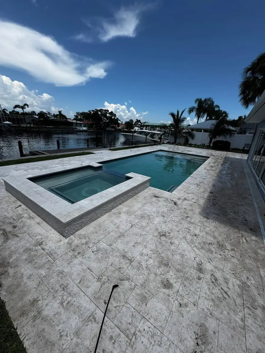 Before: a travertine pool deck and spa on a canal, the stone dull and darkened.