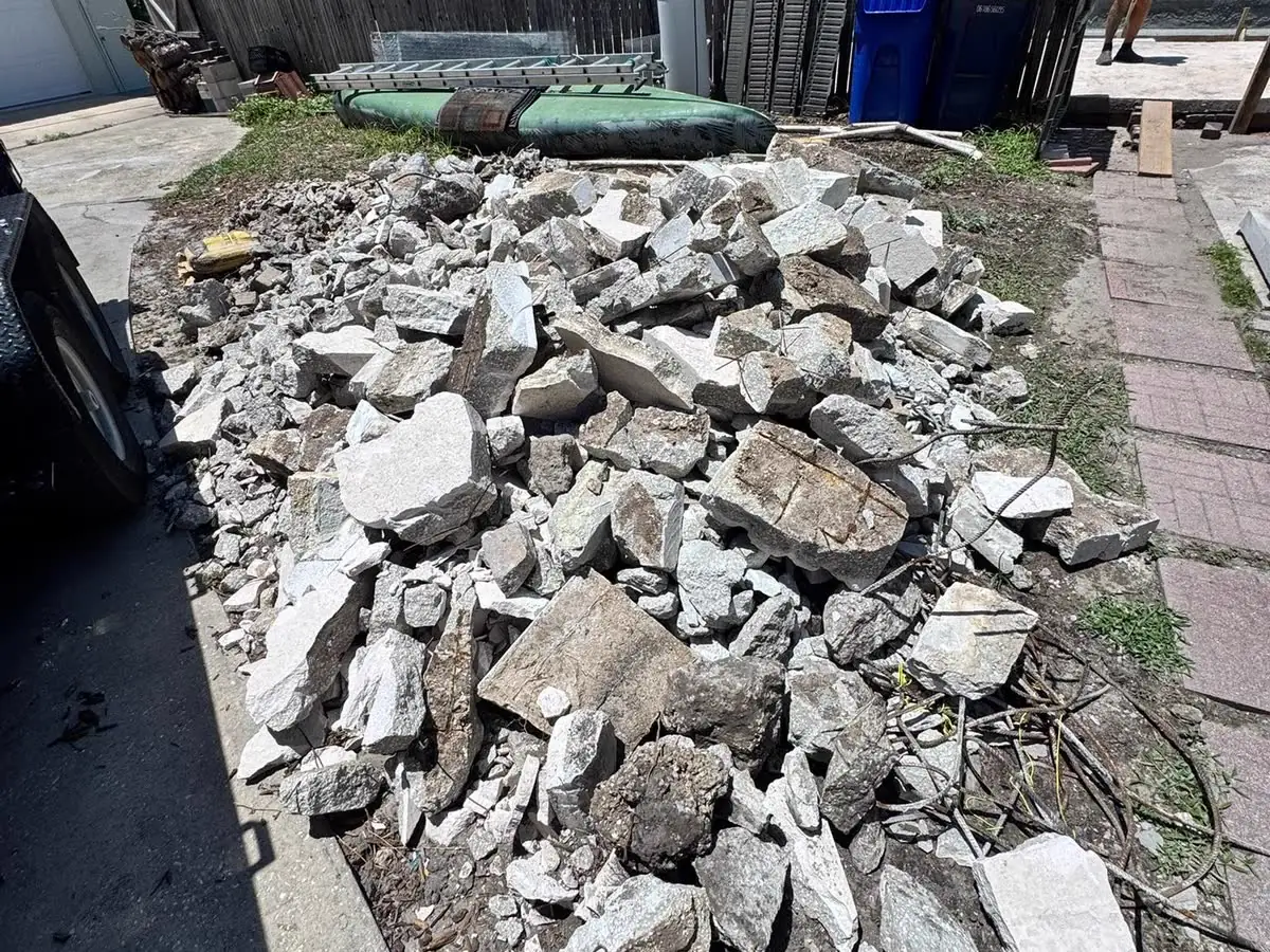 A pile of broken concrete and debris beside a yard, ready to be hauled away.