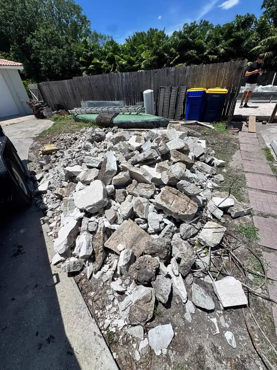 A pile of broken concrete and debris beside a yard, ready to be hauled away.