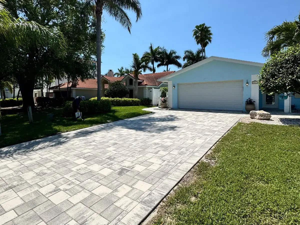A grey paver driveway leading to a house and garage.