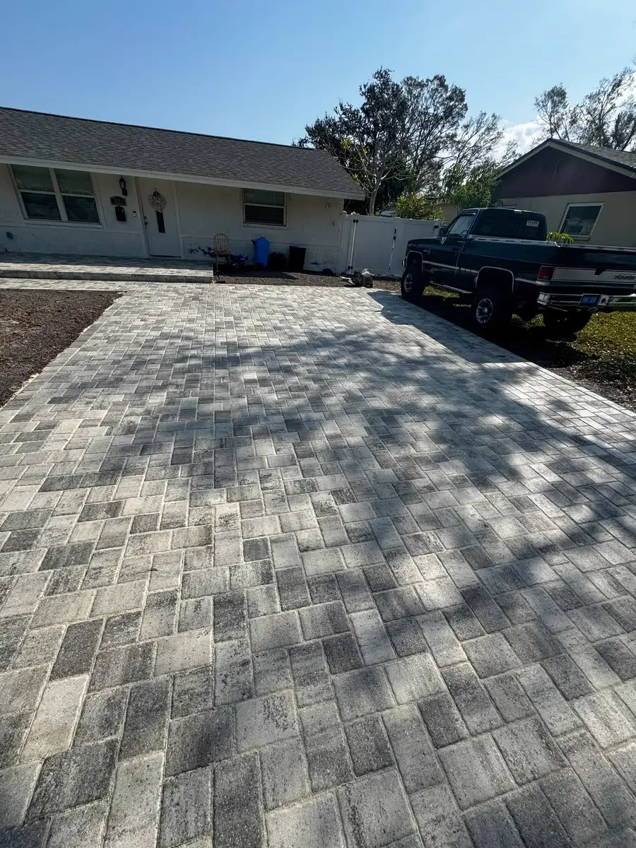 A grey paver driveway in front of a ranch house.