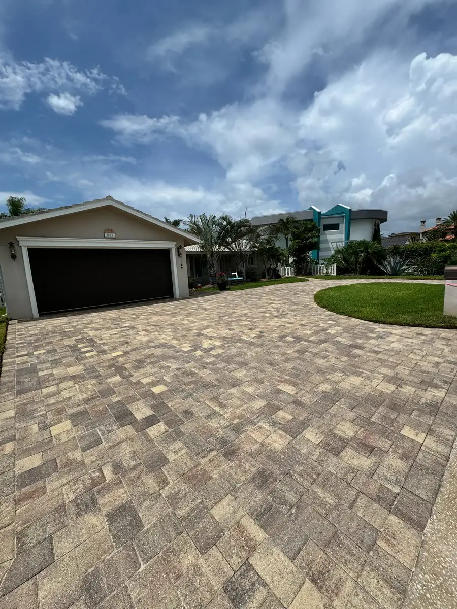 A paver driveway curving up to a house and garage.