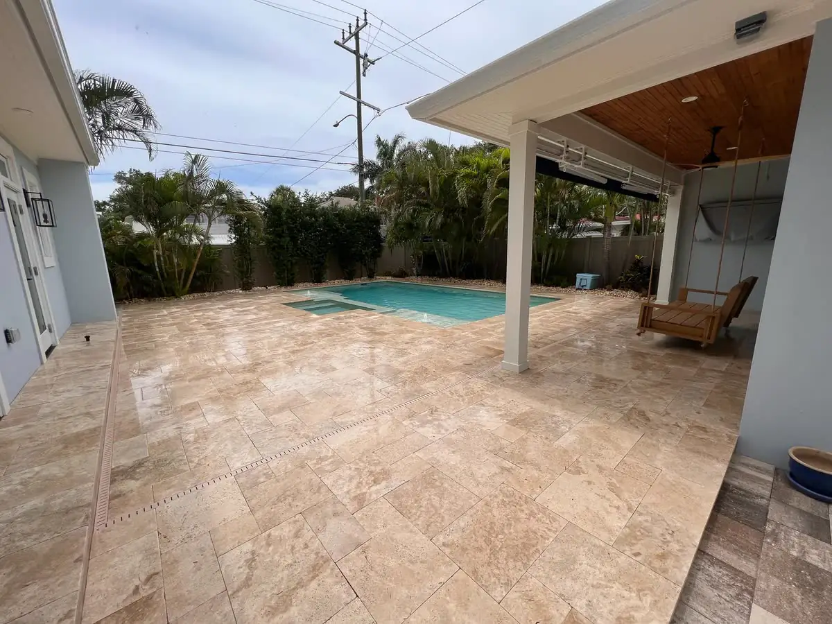 A travertine pool deck under a covered patio.