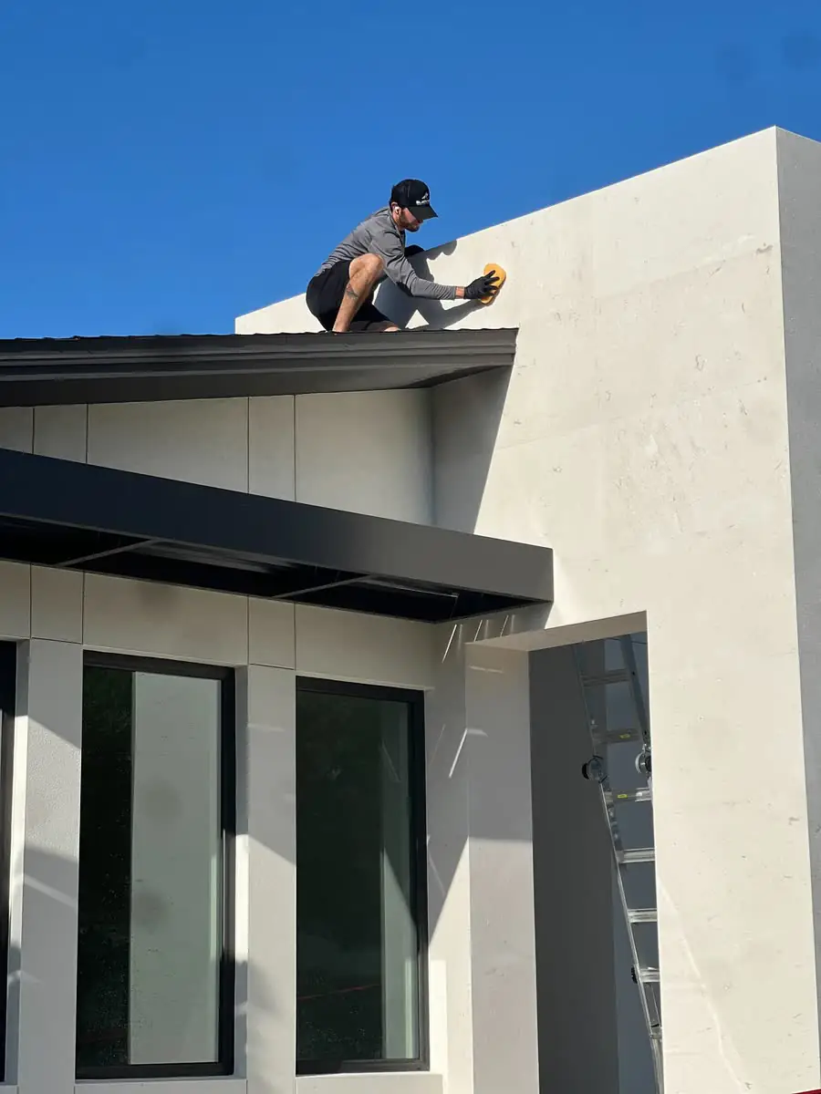 One of the crew on a flat roof, cleaning the top of a modern house.