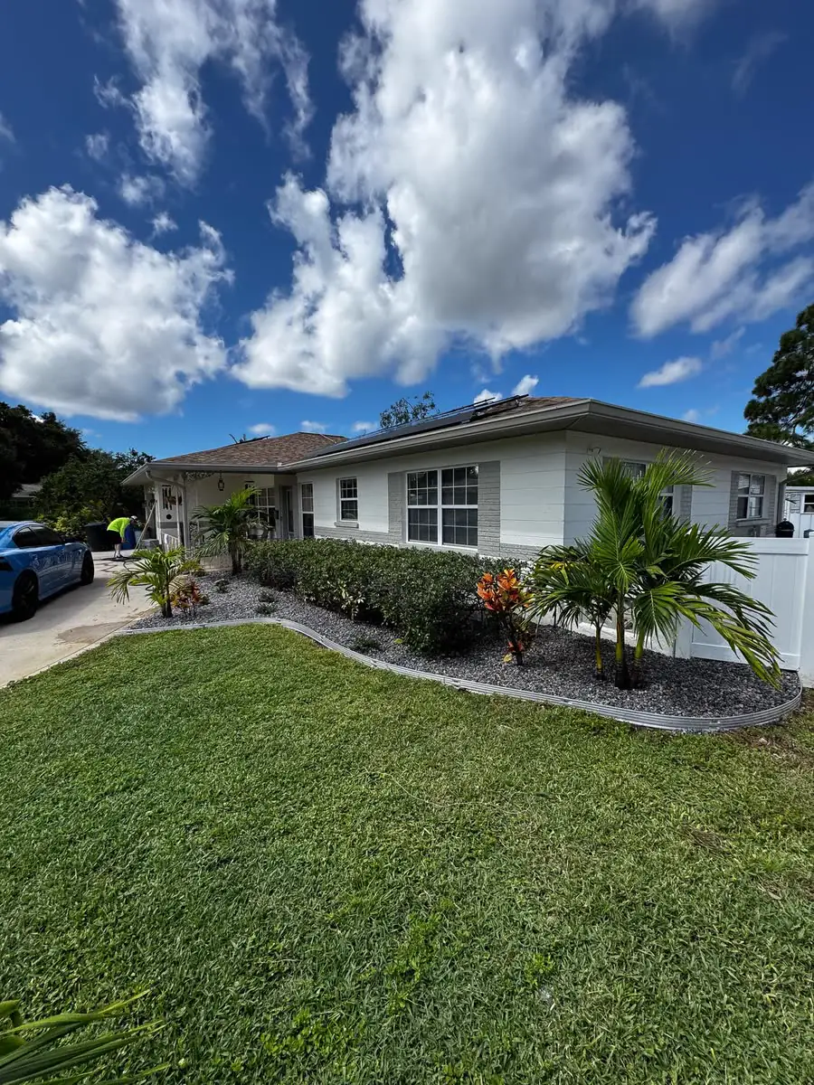 Fresh grey rock beds with palms along a front lawn.
