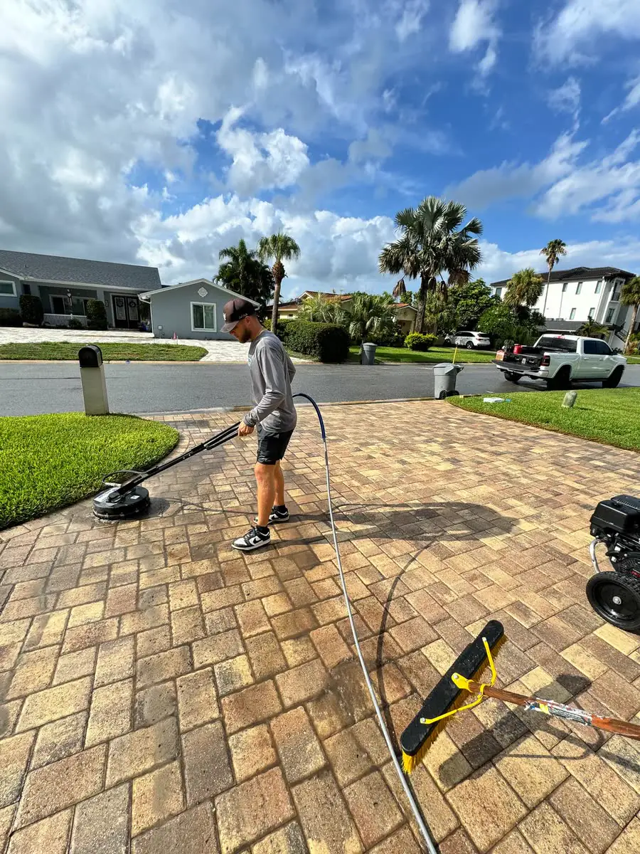 One of the crew washing a paver patio with a surface cleaner.