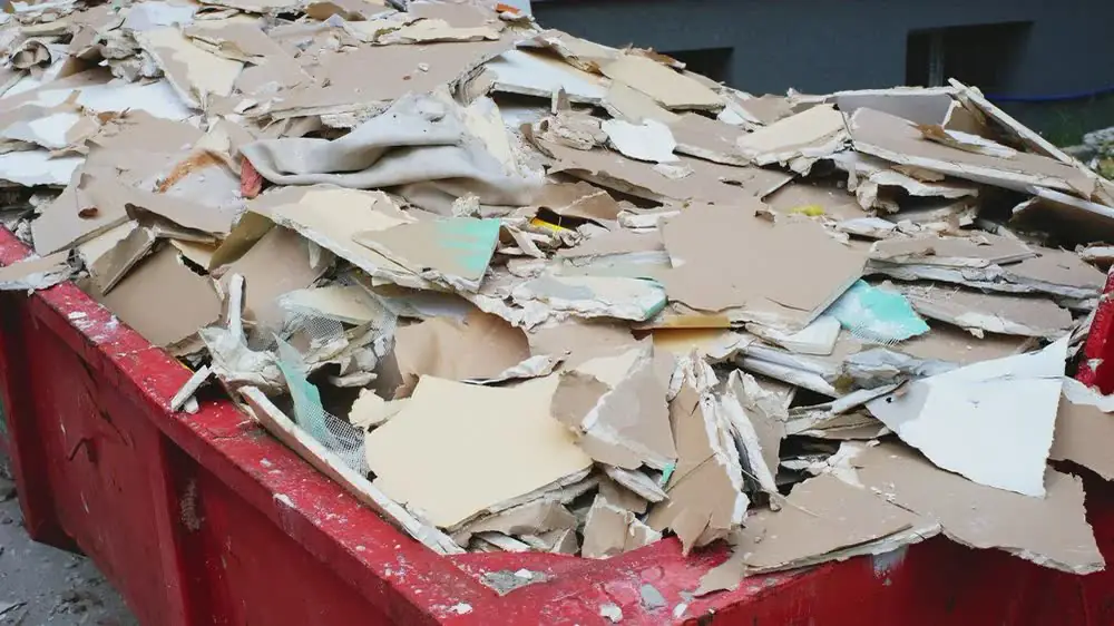 A dumpster full of broken tile and debris.