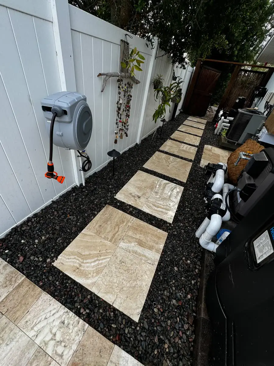 Stepping stones set in black rock along the side of a house.