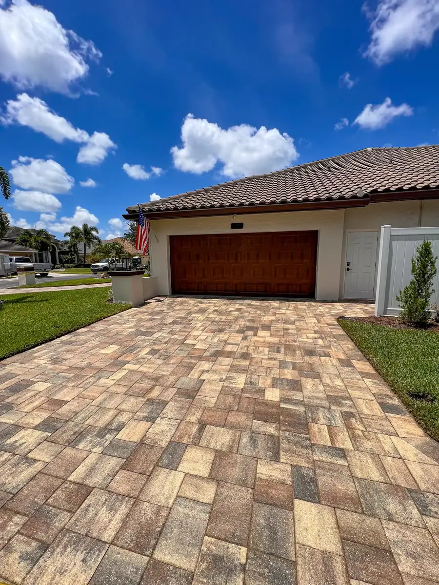A paver driveway leading to a wood garage door.