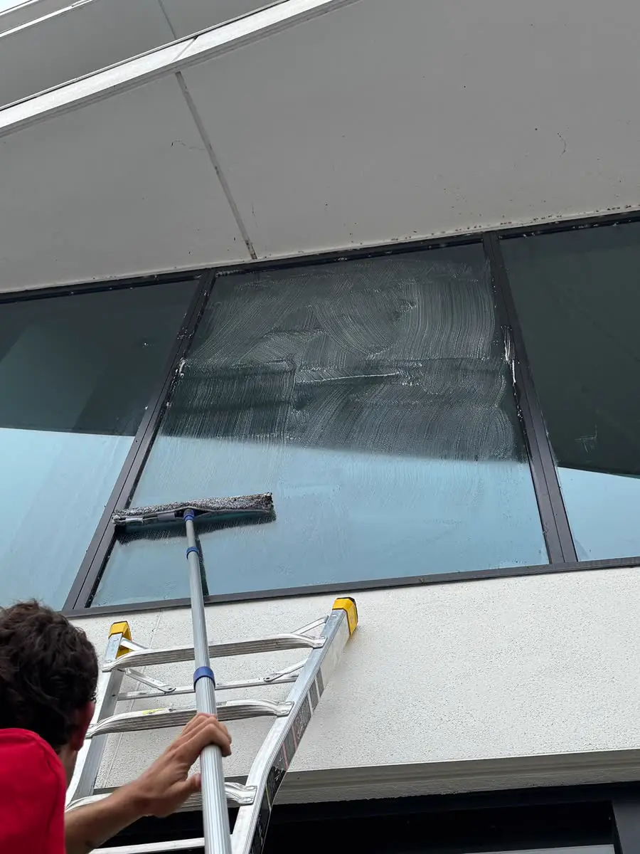 Cleaning a high window from a ladder.