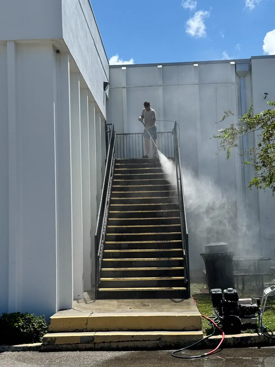 Washing a tall outdoor stairway between white walls.