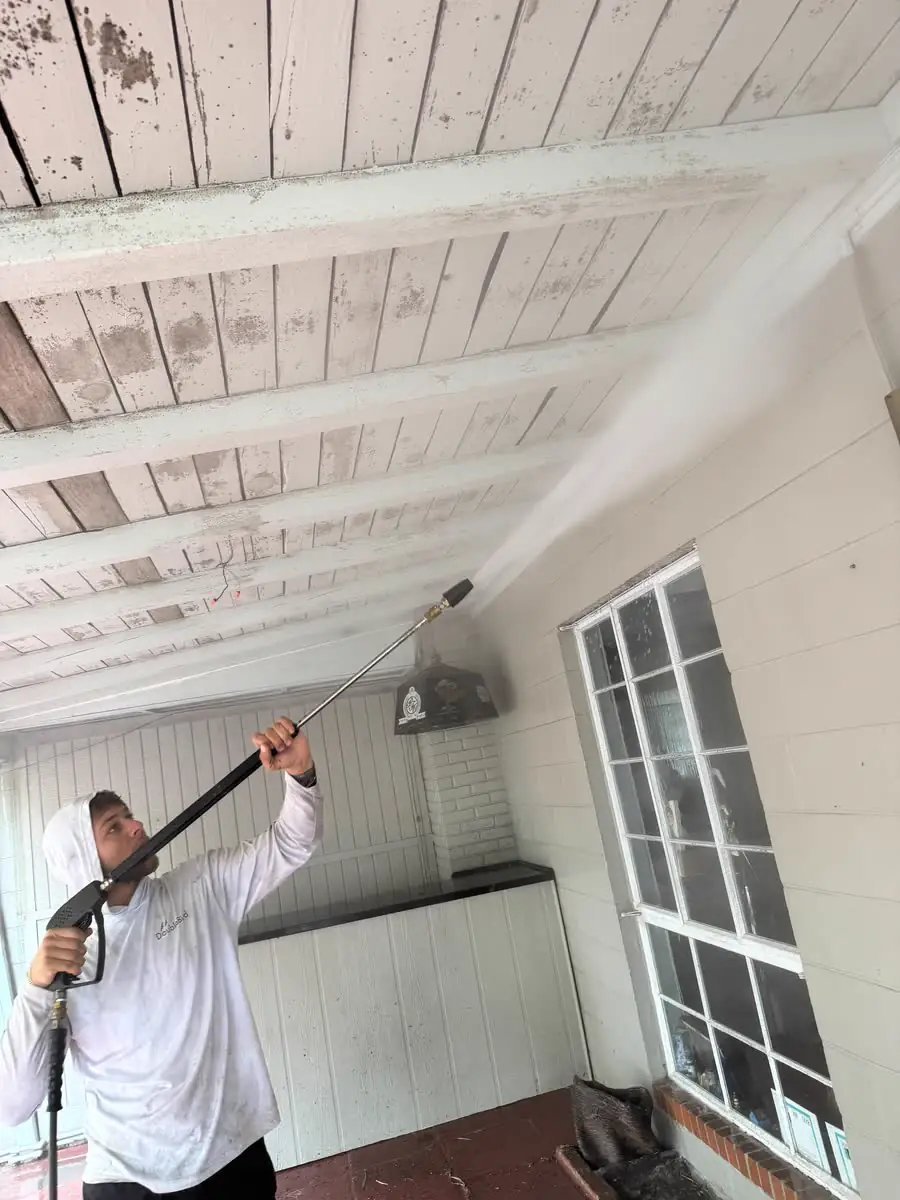 Washing the ceiling of a covered porch with a long wand.