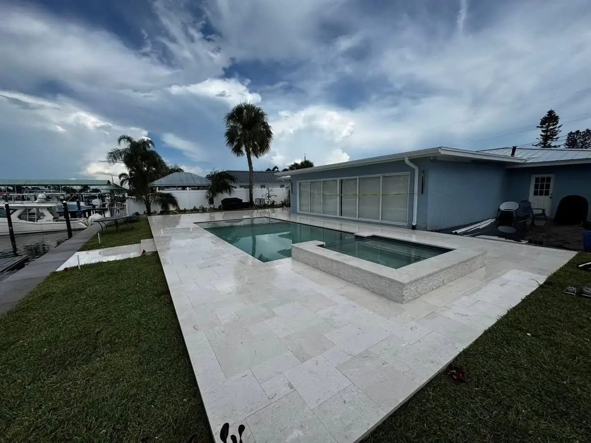 A travertine pool deck and spa, cleaned and sealed, the stone bright.