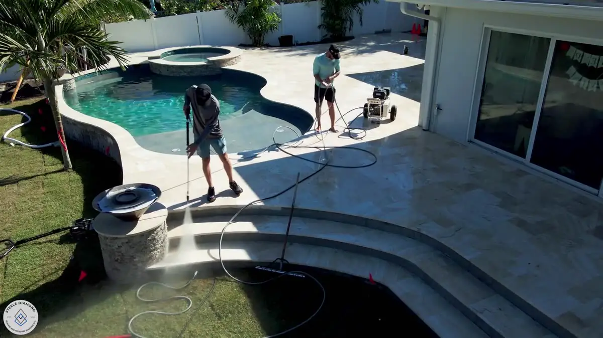 From above: two of the crew washing a travertine deck around a curved pool.