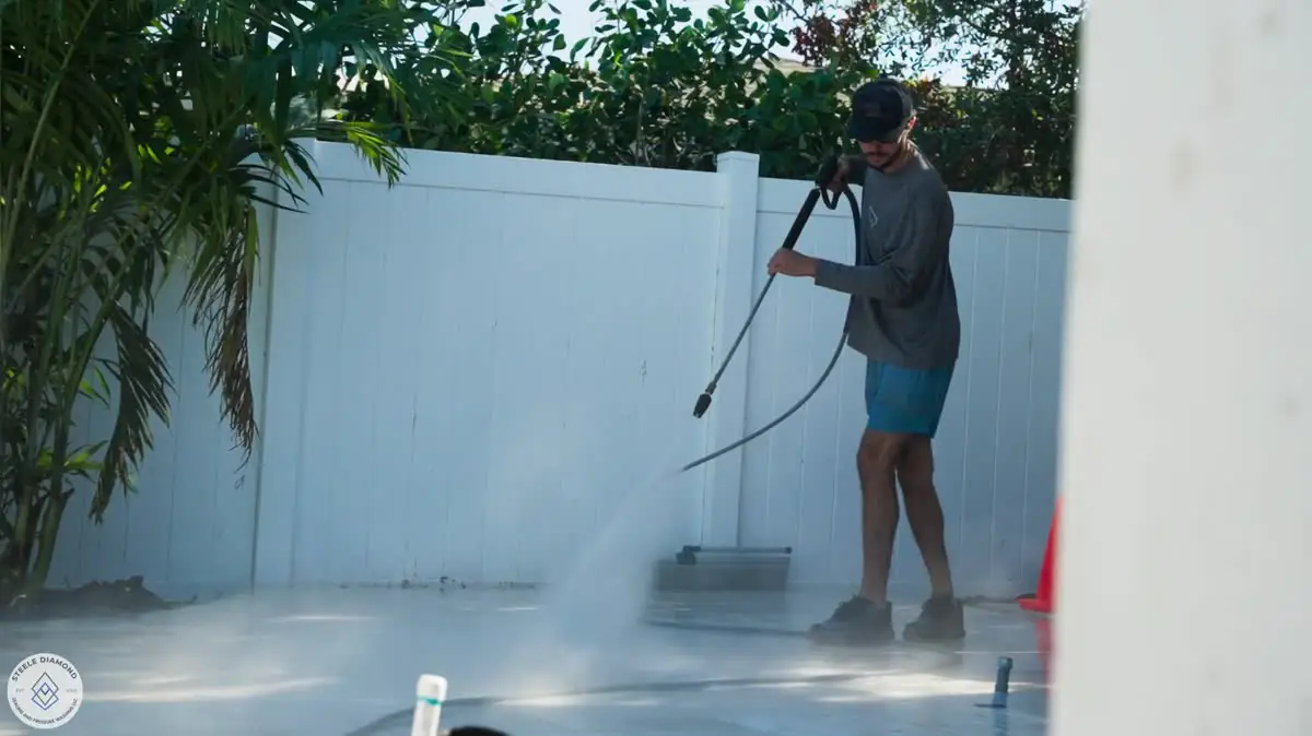Washing a deck along a white fence.
