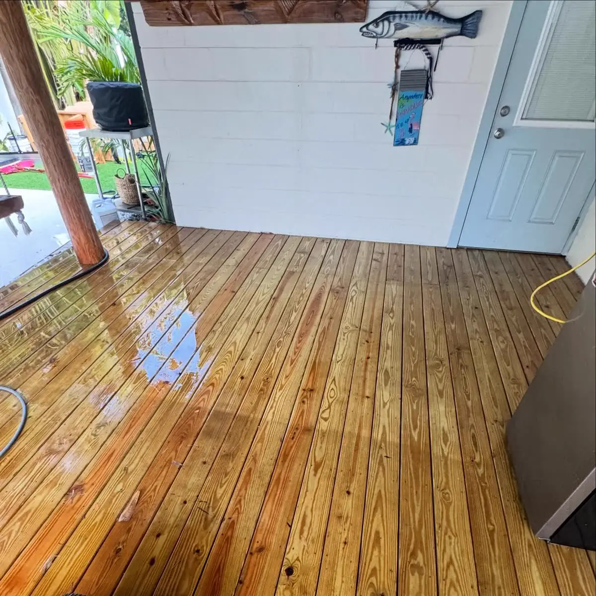 A wood deck washed clean and still wet, outside a white door.